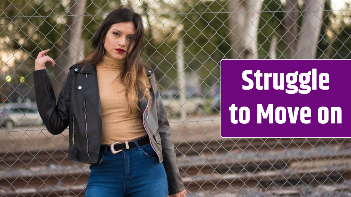 Portrait of young woman standing by chainlink fence.